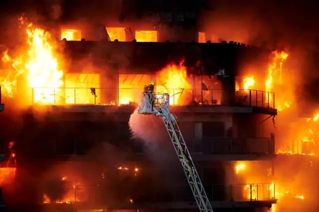 A firefighter works at the scene during the building fire in Valencia, Spain.