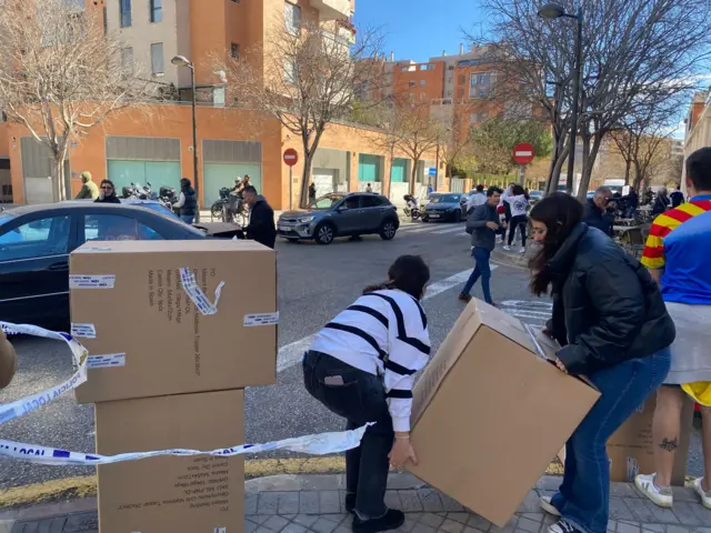 Two women lift a box in a street in Valencia