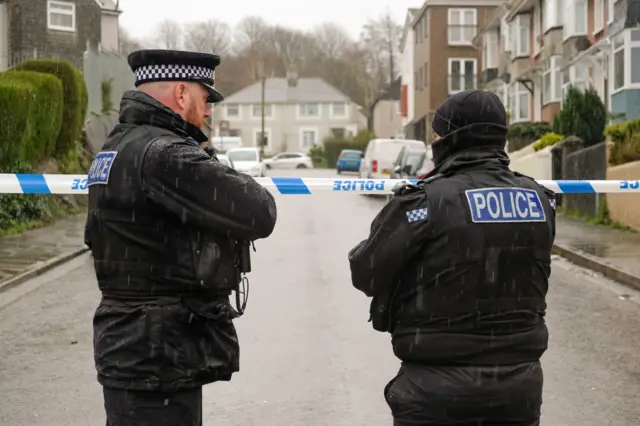 Emergency personnel by the cordon after a suspected Second World War explosive device was discovered in a garden on St Michael Avenue in Plymouth