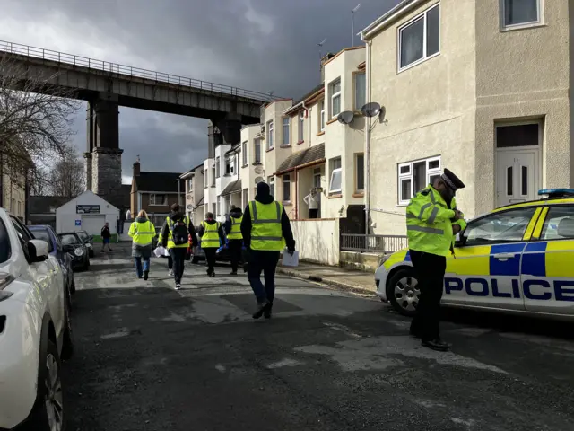 Emergency workers walking around the Keyham bomb cordon