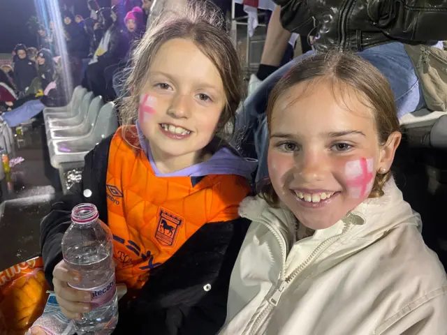 Two young England fans smile in the rain.