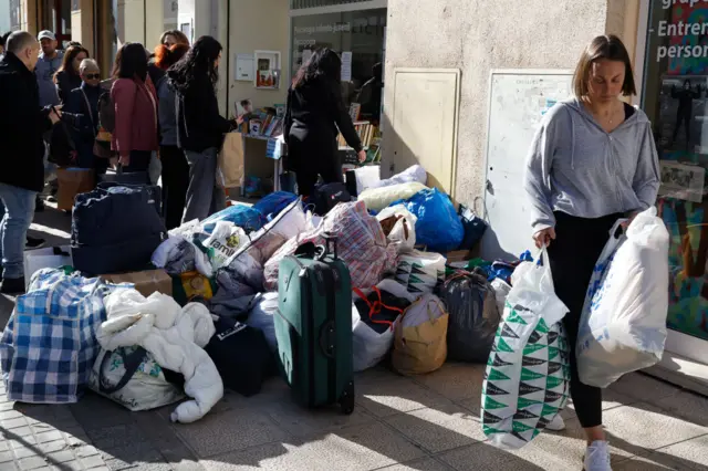 Neighbours bring clothes for the residents of the fire-ravaged apartment block n 23 February 2024.