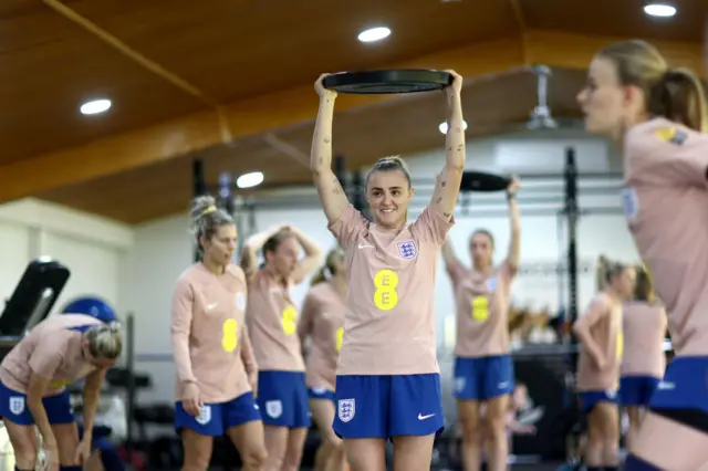 Georgia Stanway holds a weight above her head during an indoor training session.