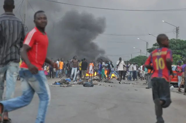 Supporters of Ivory Coast's presidential candidate Alassane Ouattara gather in the street of Abidjan as tyres burn on December 3, 2010 after the head of the Ivorian Constitutional Council, a close ally of the incumbent Laurent Gbagbo, claimed Gbagbo won the election