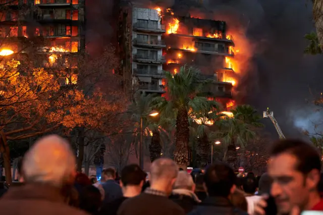 People pictured outside a building burning in flames .