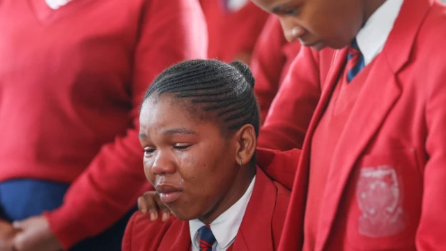 Students crying and comforting each other at the funeral.