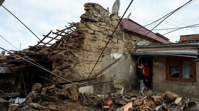 Local women stand next to their house heavily damaged by a Russian drone strike