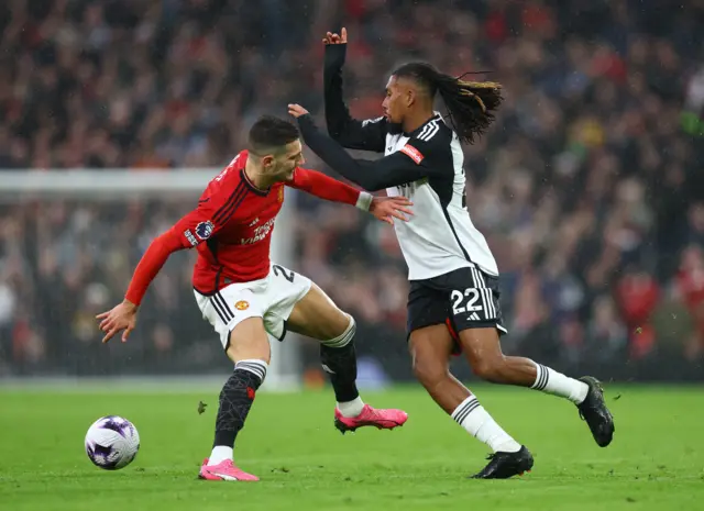 Alex Iwobi in action with Manchester United's Diogo Dalot