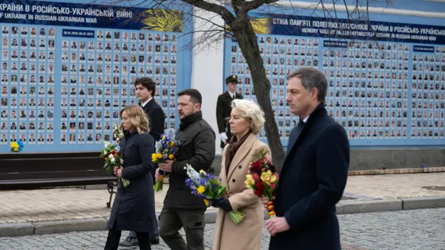 The five European leaders walk in a line down a street in Kyiv, each holding a bunch of flowers