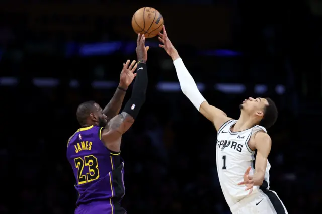 LeBron James attempting a three point shot as Victor Wembanyama reaches to block the attempt