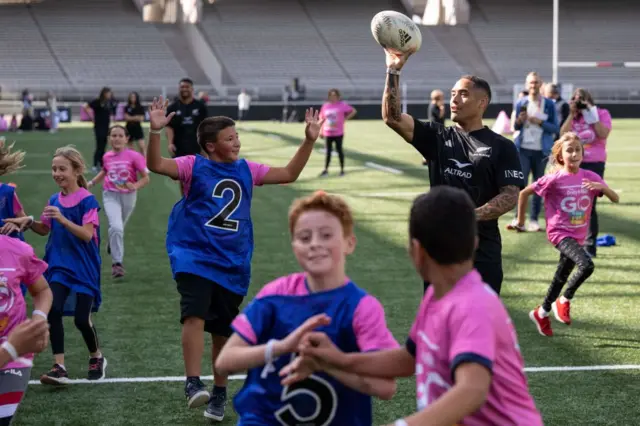 New Zealand's scrum-half Aaron Smith plays rugby with children as he attends an event promoting sports for children at the Gerland Stadium in France during the 2023 Rugby World Cup.