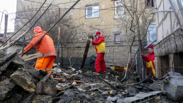 Rescuers work at the site of a damaged building after drone debris fell