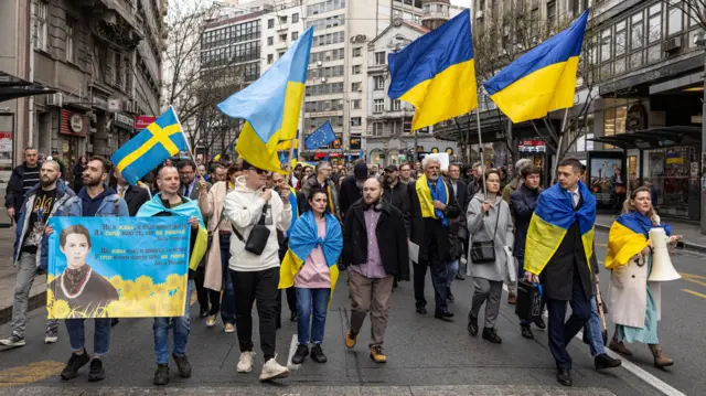 A crowd of people carrying Ukrainian flags in Belgrade, Serbia