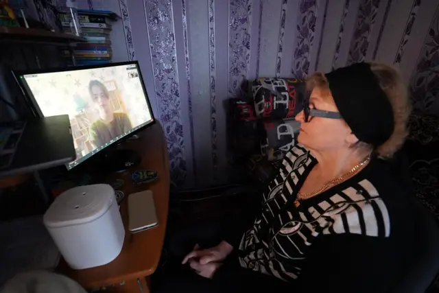 Valentyna on a video call with her son Vlad who is seen through the computer screen