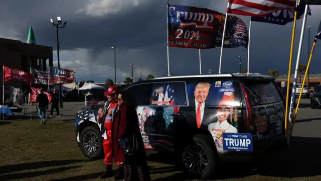 Supporter of former U.S. President and Republican presidential candidate Donald Trump pose in from of a decorated vehicle ahead of his South Carolina Republican presidential primary election night party in Columbia, South Carolina, U.S. February 24, 2024