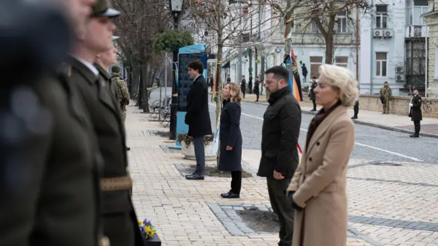 The leaders stand in front of a line of Ukrainian armed forces personnel after laying the wreaths at their feet