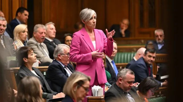 Liberal Democrat MP for St Albans Daisy Cooper standing up in Commons and gesturing with her hands while she speaks, surrounded by other MPS on the benches