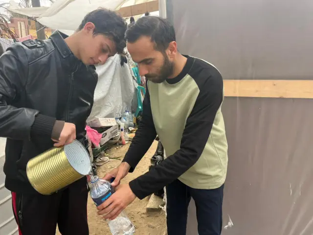 Two men in Gaza sharing water