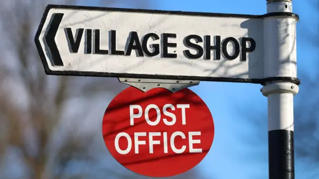 The logo of the Post Office is displayed on a Village Shop sign