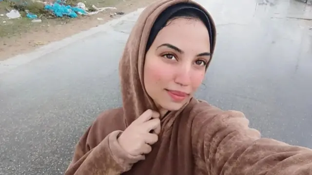 Farida Adel poses for a photograph in the street in a brown hoodie and hijab