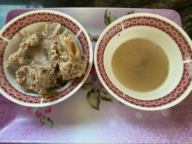 Bowl of chicken broth and bowl with chicken bones