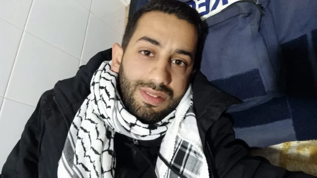 A selfie taken by Mohamed as he lays his head on a blue press vest. He wears a keffiyeh around his neck