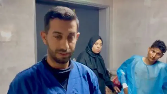 Dr Mohamed Al Sheikh wearing scrubs with a woman and a patient behind him