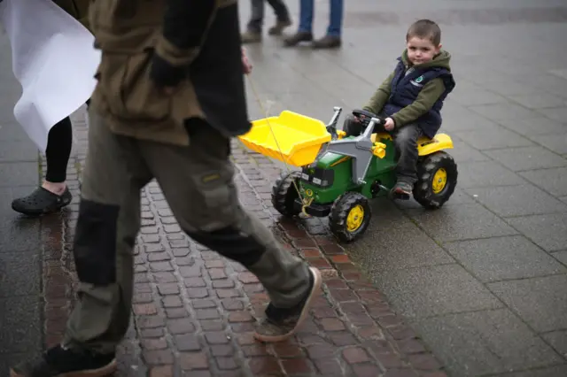 A child is pulled along on a toy tractor during protests outside the Senedd on February 28, 2024 in Cardiff, Wales