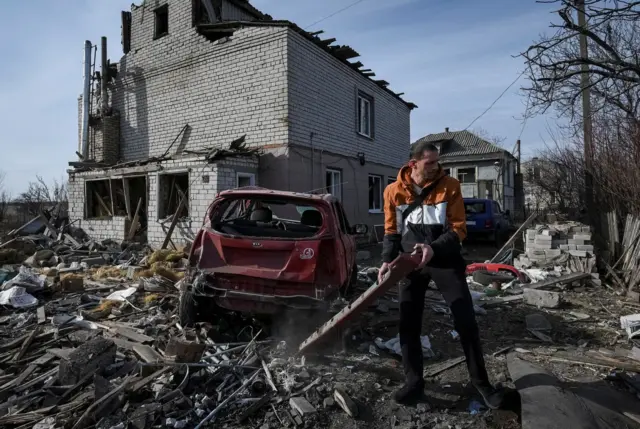 A local resident prepares a damaged car to be towed, near a residential building damaged during a Russian drone strike, amid Russia's attack on Ukraine, in Dnipro, Ukraine.