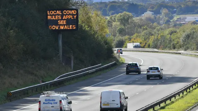 A matrix sign on the M4 motorway near Cardiff in Wales reminds motorists of Covid-19 local rules