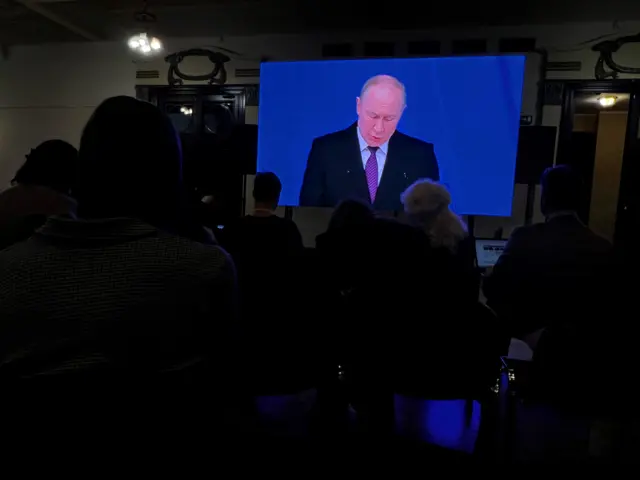 Putin's speech is shown on a screen in a press room for Western journalists