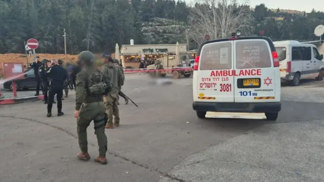 An ambulance is seen parked with soldiers walking nearby