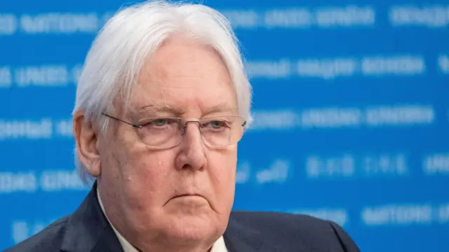 Martin Griffiths sits in front of a blue background