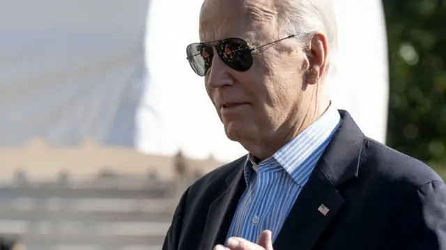 Joe Biden, wearing sunglasses, speaks to reporters outside the White House