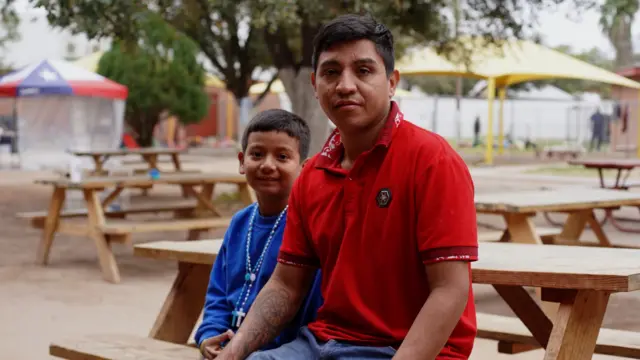 A boy and a man sitting on a park bench