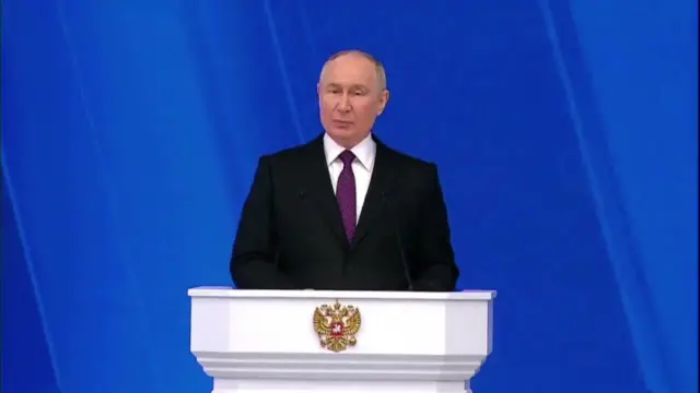 Putin begins speaking at a white lectern