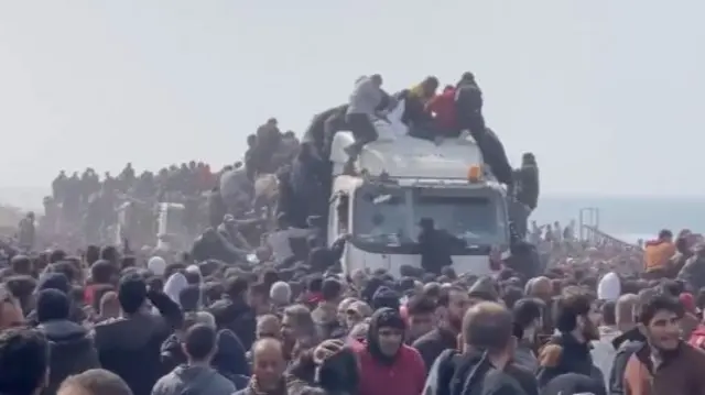 Gazans clamber on to a truck to secure aid during a delivery on 19 February