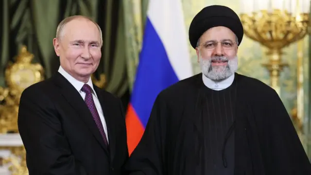 Putin and Raisi shake hands and smile as they pose for an photo