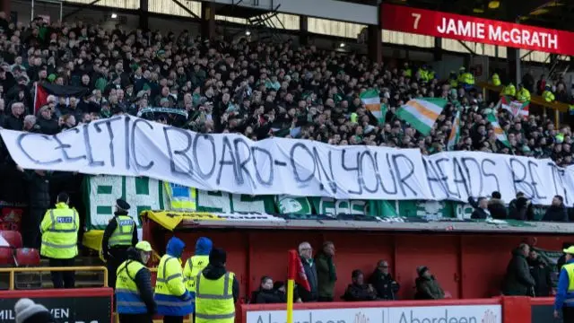 Celtic fans holding a banner at Pittodrie