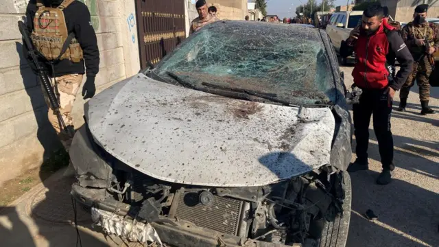 Security forces inspect a damaged car at the site of a U.S. airstrike in al-Qaim, Iraq