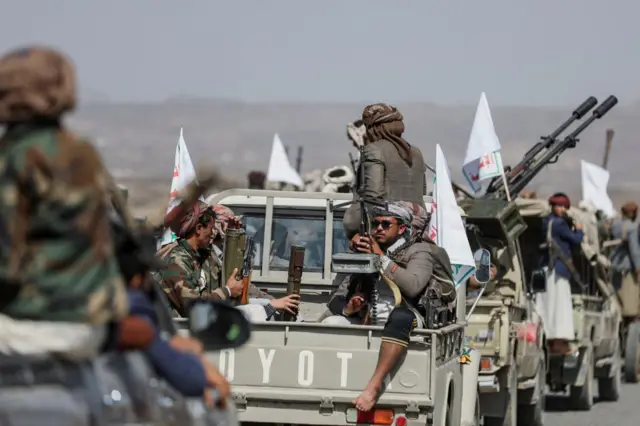 Armed Houthi rebels ride in the back of vans