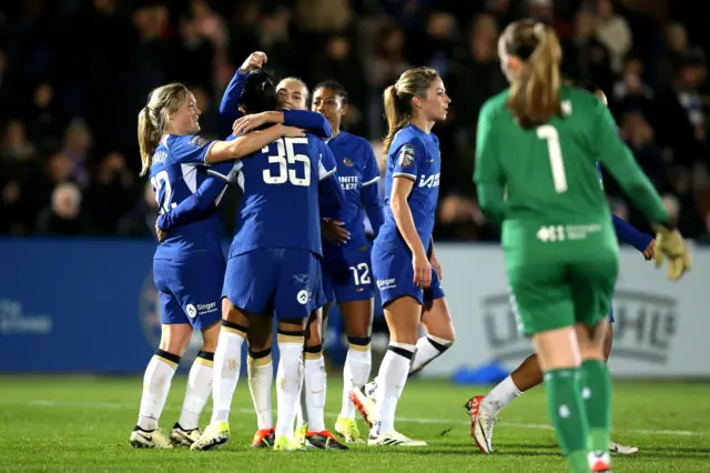 Chelsea players celebrate their goal with Everton stopper Brosnan in the background.