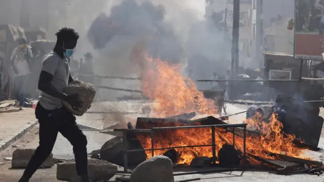 A Senegalese demonstrator carries a stone during clashes with riot police as they protest against the postponement of the Feb. 25 presidential election, in Dakar, Senegal February 4, 2024.