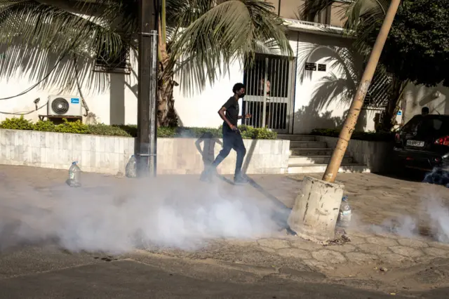 A protester runs from tear gas outside the General Assembly in Plateau, Dakar.