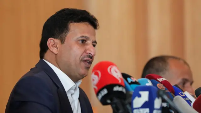 Hussein al-Ezzi, the deputy foreign minister in the Houthi-led government, is shown in the centre of a news conference panel