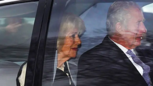 King Charles and Queen Camilla sit in the back of a car