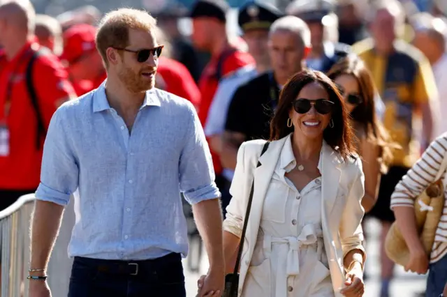 Prince Harry and his wife Meghan wearing sunglasses and holding hands in Dusseldorf in September 2023