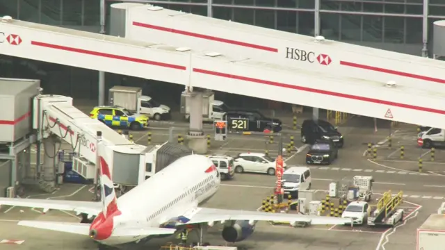 A police car and three black cars seen near the runway at Heathrow airport