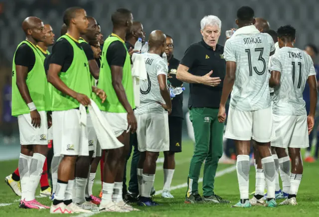 Hugo Broos gives instructions to his South Africa players during a water break.