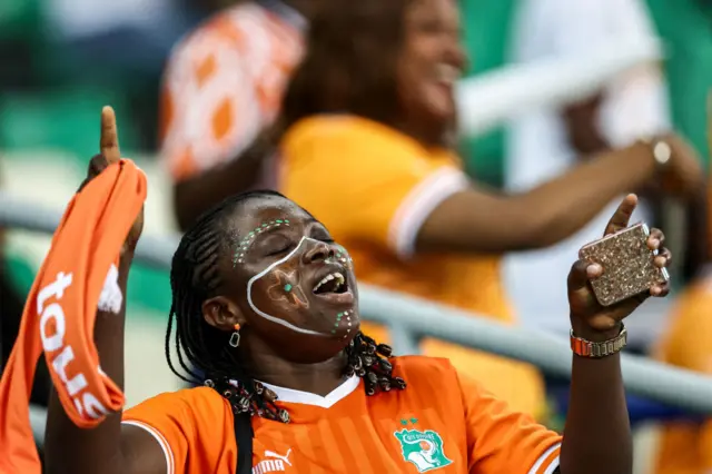 A fan sings songs of support in her team's colours.